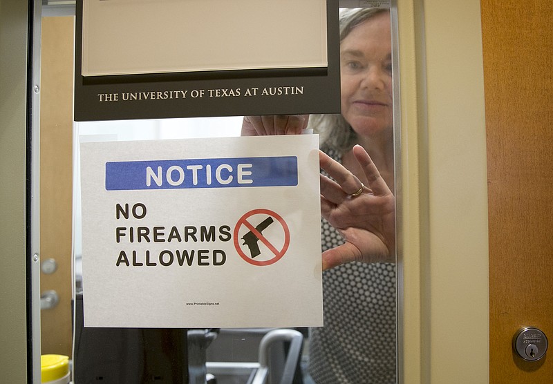 University of Texas at Austin Anthropology professor Pauline Strong posts a sign prohibiting guns at her office on the first day of the new campus-carry law Monday, Aug. 1, 2016. The law pushed by Gov. Greg Abbott and the Republican legislative majority will make Texas one of a handful of states that guarantee the right to carry concealed handguns on campus.