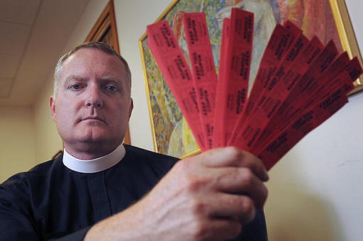 In this July 27, 2016 photo, Rev. Jeremy Lucas of Christ Church Episcopal Parish holds the 150 tickets that he purchased in an all-star softball team's raffle to win an AR-15 assault rifle in Lake Oswego, Ore. Lucas may have run afoul of Oregon law when he transferred the assault rifle, which he says he tried to win in order to destroy it, to a friend for safekeeping without performing a background check. (Vern Uyetake/Lake Oswego Review via AP)