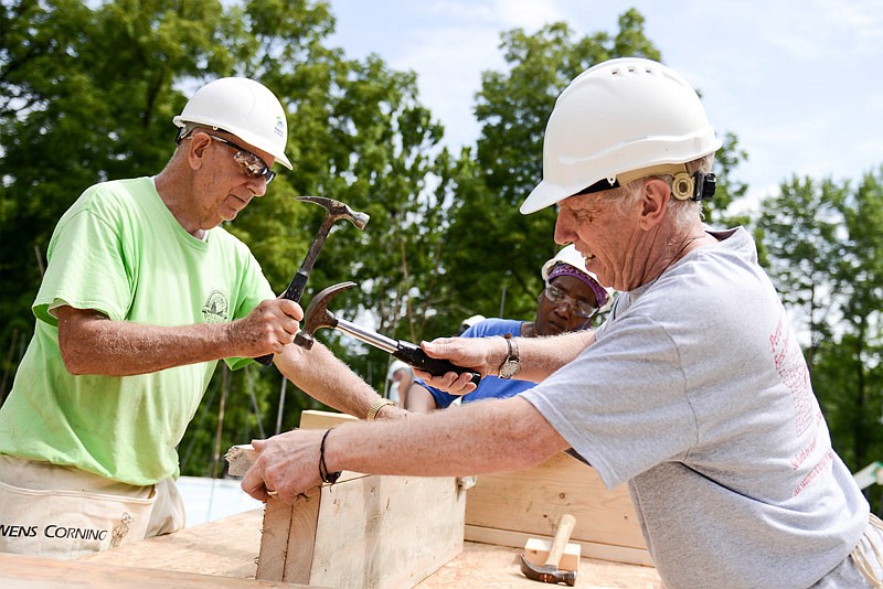Dave Henry, right, Bob Sfreddo and Judy McCombs, middle, hammer wall sections together for her home.