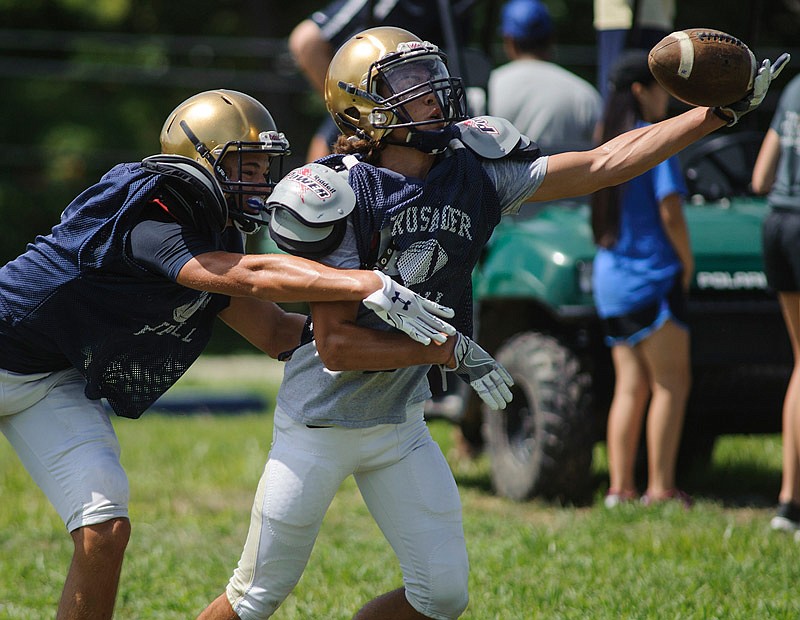 Helias wide receiver Joe Randazzo tries to haul in the one-handed catch while being closely defended by defensive back Adam Wilbers during a morning practice session Saturday, Aug. 6, 2016.