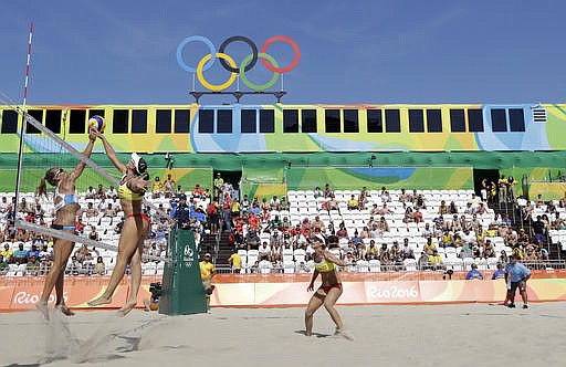 Spain's Liliana Fernandez, center, hits over Argentina's Ana Gallay, left, during a women's beach volleyball match at the 2016 Summer Olympics in Rio de Janeiro, Brazil, Saturday, Aug. 6, 2016.