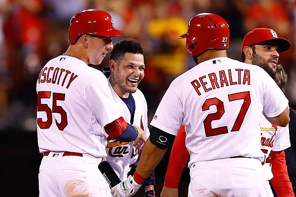 Yadier Molina is congratulated by Cardinals teammates Stephen Piscotty and Jhonny Peralta after driving in the game-winning run in Monday night's 5-4 victory against the Reds at Busch Stadium.
