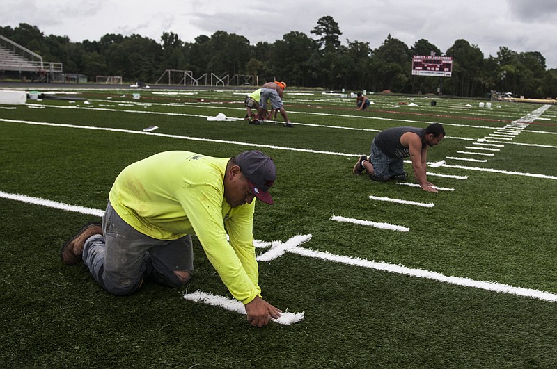 Mario Toscareno, left, and Geovani Tegada, right, with Symmetry Turf Sports Field Construction install the yard line marks on a new turf field Monday, Aug.15, 2016 at Harris Field behind Liberty-Eylau High School. 