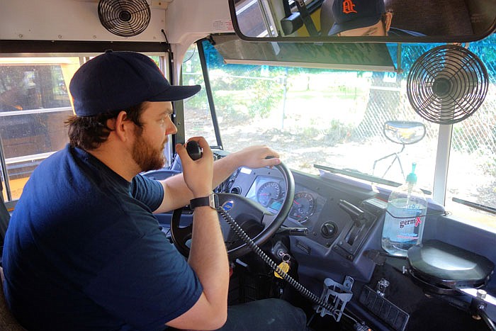 Driver Jakob Shill uses a radio in his school bus Tuesday morning.