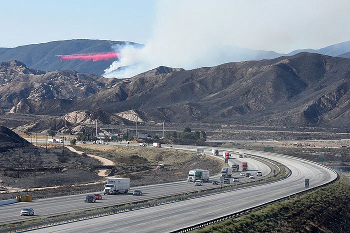 A DC-10 drops fire retardant on a wildfire Tuesday as southbound Interstate 15 remains closed in the Cajon Pass, California. The California Highway Patrol reopened I-15 late Wednesday night, while the southbound side remained closed until Thursday.