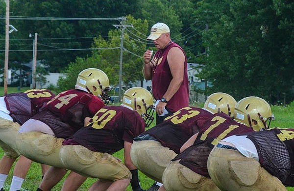 Eldon head coach Shannon Jolley runs through drills with his offensive linemen during practice earlier this month.