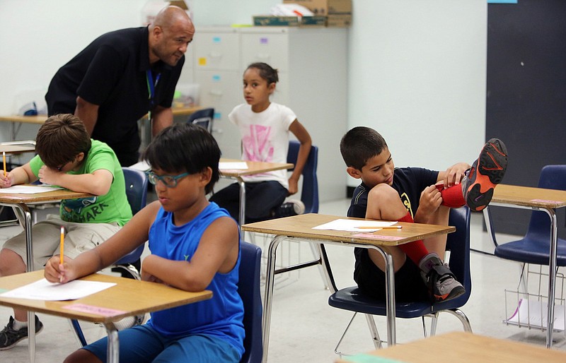 Teacher Herbert McArthur, Jr. works with Samantha N. as Jesus G. gets a little distracted from his studies during a special summer program for children with ADHD run by FIU.