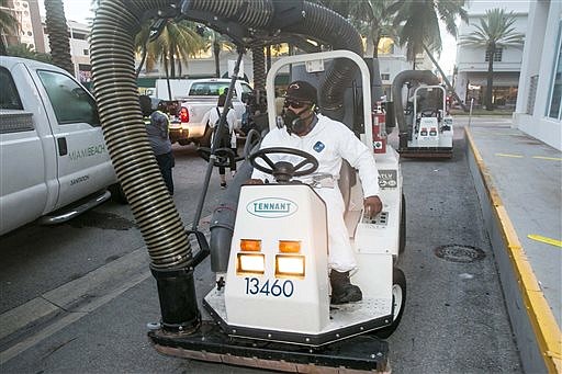 A City of Miami Beach Sanitation worker gets ready to clean the alleyways of South Beach, sucking up still waters and debris with a mobile vacuum, Friday, Aug. 19, 2016, Miami Beach, Fla., as part of the city's Zika clean-up. (C.M. Guerrero/El Nuevo Herald via AP)
