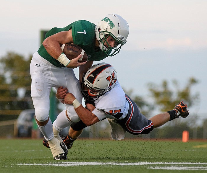 Jake Van Ronzelen of Blair Oaks tries to stay on his feet as Kirksville safety Blake Lewis
wraps up his legs during their game in Wardsville on Friday, Aug. 19, 2016.