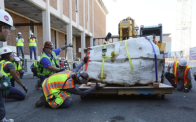 Encased in plaster, the 4-foot-long, 2,500-pound remains of a Tyrannosaurus rex skull, is moved by fork lift to a wheeled cart behind the loading dock of the Burke Museum in Seattle.
