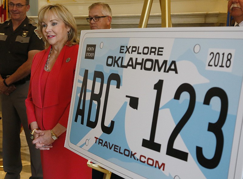 Oklahoma Gov. Mary Fallin, foreground, speaks at a news conference Monday to reveal a new design for the state license plate in Oklahoma City. Every Oklahoma motorist will pay an additional $5 for a new plate that features the outline of the state bird, a scissortail flycatcher, on a blue background. Oklahoma Highway Patrol Chief Ricky Adams, left, looks on.