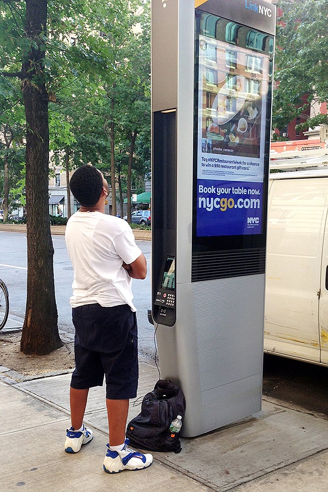 A man charges his phone at a Wi-Fi kiosk on Broadway and 86th Street in New York.