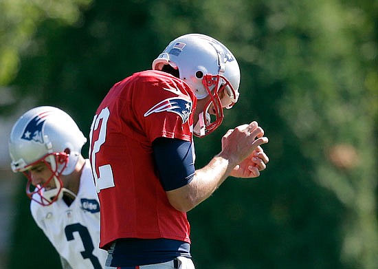 Patriots quarterback Tom Brady pauses to look at his hand during practice Tuesday in Foxborough, Mass.  Brady cut his right thumb with a pair of  scissors last week.