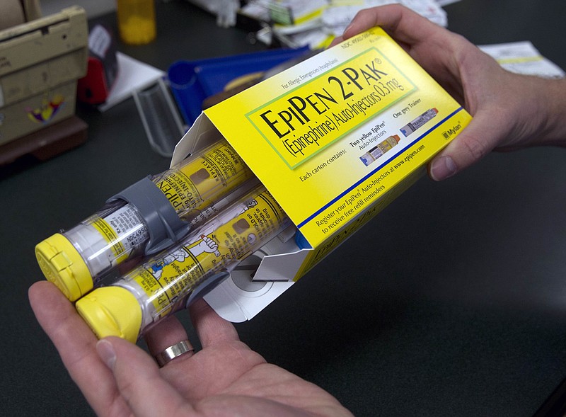 In this Friday, July 8, 2016 photo, a pharmacist holds a package of EpiPens, an epinephrine autoinjector for the treatment of allergic reactions, in Sacramento, Calif. Price hikes for the emergency medicine have made its maker, Mylan, the latest target for patients and politicians infuriated by soaring drug prices. 