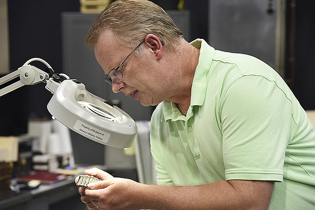 Charles Machon looks for identifying marks on an unusual recent acquisition. The Museum of Missouri Military History has just acquired several hundred items from the National Military Heritage Museum in St. Joseph, which has recently closed. Items range from prior to World
War I to Vietnam era memorabilia.