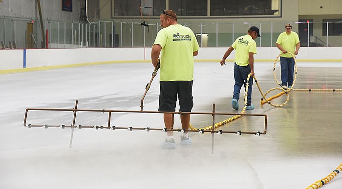 Doug McBride looks over his shoulders to keep an eye on the paint mixture being propelled from the spray jets behind him. In front of him, Joe Schulte and Austin Kliethermes carry the hose containing the paint. There are three layers of paint on top of several layers of ice, and several more layers of water will be sprayed on top to let freeze. Jefferson City Parks and Recreation staff has been busy working to clean the Washington Park Ice Arena after recent flash flooding caused tens of thousands of dollars of damage.