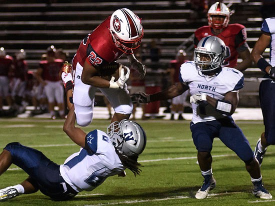 Jefferson City running back Rashaun Woods bowls over a McCluer North player on his way to a big gain during last Friday night's game at Adkins Stadium.