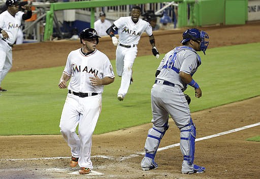 Miami Marlins' Jose Fernandez, left, and Dee Gordon, rear, score on a single by Christian Yelich as Kansas City Royals catcher Salvador Perez (13) waits for the throw during the sixth inning of a baseball game, Wednesday, Aug. 24, 2016, in Miami. 