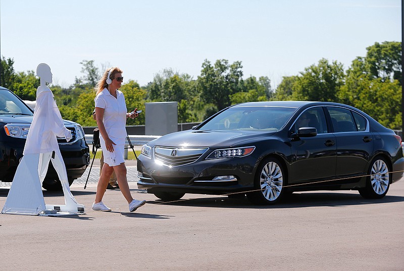 In this July 20, 2015 file photo, a pedestrian crosses in front of a vehicle as part of a demonstration at Mcity on its opening day on the University of Michigan campus in Ann Arbor, Mich. Automakers say cars that wirelessly talk to each other are finally ready for the road. The cars hold the potential to dramatically reduce traffic deaths, improve the safety of self-driving cars and someday maybe even help solve traffic jams. Government and industry have spent more than a decade and more than $1 billion researching and testing the technology, known as vehicle-to-vehicle communications, or V2V.  