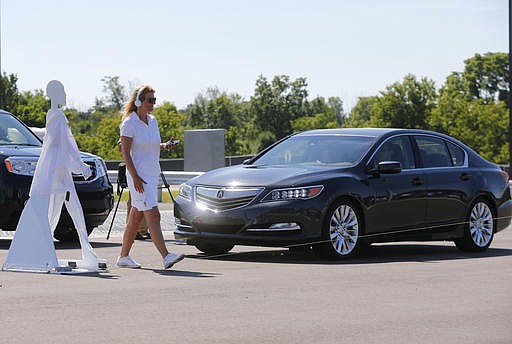 In this July 20, 2015 file photo, a pedestrian crosses in front of a vehicle as part of a demonstration at Mcity on its opening day on the University of Michigan campus in Ann Arbor, Mich. Automakers say cars that wirelessly talk to each other are finally ready for the road. The cars hold the potential to dramatically reduce traffic deaths, improve the safety of self-driving cars and someday maybe even help solve traffic jams. Government and industry have spent more than a decade and more than $1 billion researching and testing the technology, known as vehicle-to-vehicle communications, or V2V. 