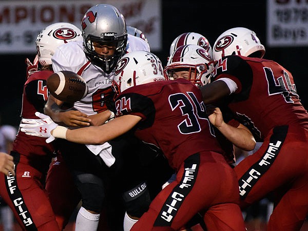 Springfield Central quarterback Danny Adams coughs up the football after taking several hard hits while being gang tackled by the Jefferson City defense Friday night at Adkins Stadium.