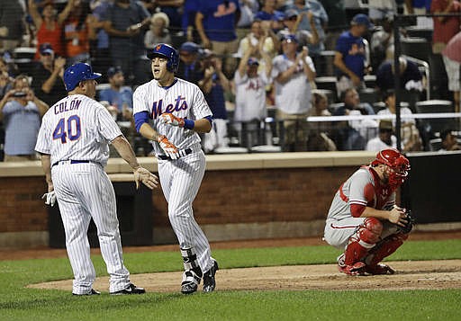 New York Mets' Wilmer Flores, center, celebrates with Bartolo Colon, left, as Philadelphia Phillies catcher Cameron Rupp, right, reacts after Flores hit a grand slam during the fifth inning of a baseball game Friday, Aug. 26, 2016, in New York. 