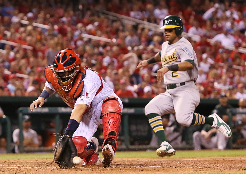 St. Louis Cardinals catcher Yadier Molina reaches for the throw as Oakland Athletics' Khris Davis, right, scores the tying run in the eighth inning during a baseball game, Saturday, Aug. 27, 2016, at Busch Stadium in St. Louis. 