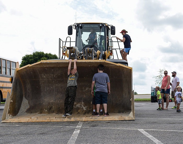 Children hang on to the edges of a bulldozer as others wait in line to check out its interior and hop in the shoes of a construction worker for a brief moment Saturday, Aug. 27, 2016 during the Mighty Machines event at Capital Mall in Jefferson City.