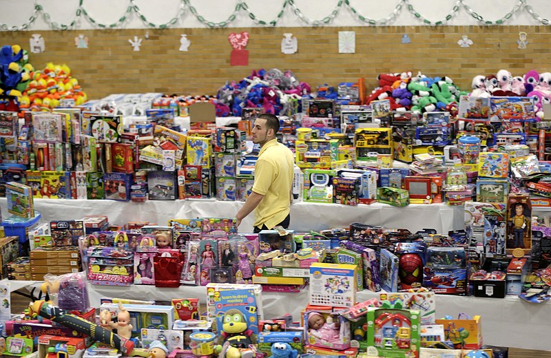 In this Friday, Dec. 21, 2012 file photo, volunteer Anthony Vessicchio of East Haven, Conn., walks past tables full of donated toys at the town hall in Newtown, Conn. Donors from around the world sent gifts, including teddy bears for children in the community of about 28,000. More than 60,000 bears accumulated in a warehouse before eventually being sent to hospitals and other charities around the globe.