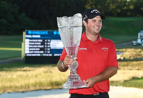 Patrick Reed smiles as he holds the trophy after winning The Barclays on Sunday at Bethpage Black in Farmingdale, N.Y.