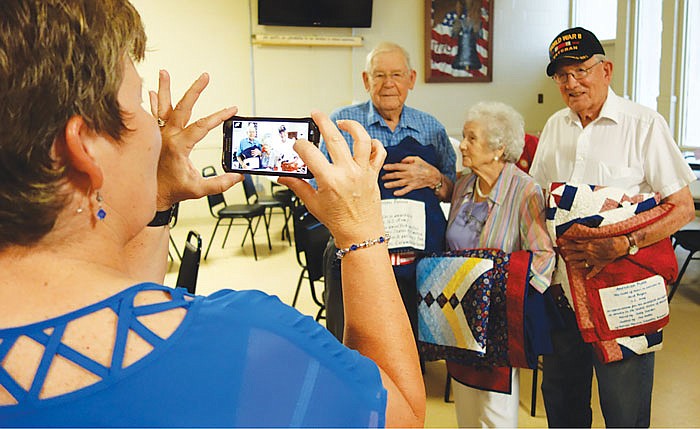 Sharon Crider takes a photo of her father, Leander Bax, left, and his two bowling buddies, Ruth Buell, middle, and Herb Meyer after Sunday's Quilts of Valor ceremony. The three World War II veterans were among 14 honored. They still bowl together locally each week.