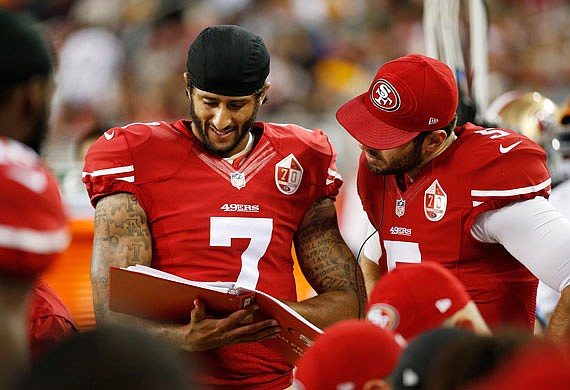 49ers quarterbacks Colin Kaepernick (left) and Christian Ponder look over a playbook on the sideline during Friday night's game against the Packers in Santa Clara, Calif.