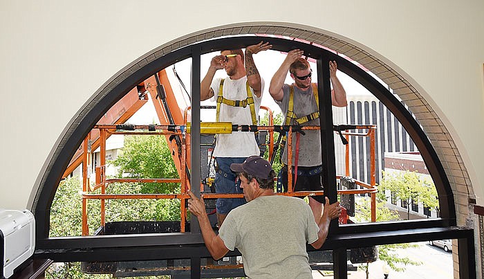 Henry Millman, in foreground, slides the bottom part of the frame into place as Jeff McMinn, left, and Dakota Chrisenberry push in the top portion. Window installation at the Cole County Courthouse and annex continues as installers from the Wilson Group place the arch-shaped window frame in a third floor corner office Monday afternoon. 