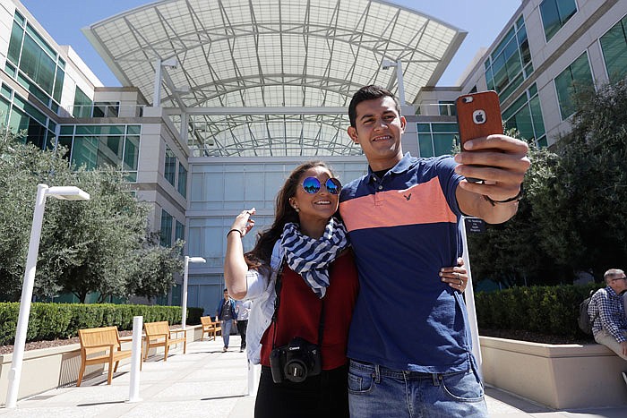 Alejandra Vicuna, left, and Andres Ballesteros, of Miami, Florida, take a selfie in front of the Apple campus in Cupertino, California. There's a quirky twist in tourism emerging amid the Silicon Valley whirlwind of innovation that has tethered everyone to their smartphones. 