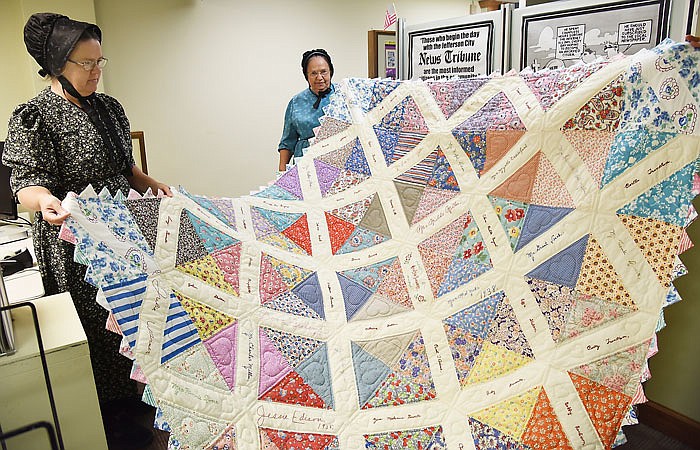 Anna Martin, left, and her mother, Marian Martin, hold up a quilt they worked on together. They found quilt blocks in a bag someone had donated to the Salvation Army and after putting the quilt together are now on a mission to find the blocks' creators or family members.