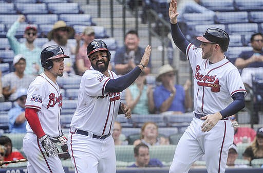 Atlanta Braves' Matt Kemp celebrates at home plate with Freddie Freeman, right, and Jace Peterson, left, after scoring on a two-run single line drive to right field by Anthony Recker during the fifth inning of a baseball game against the San Diego Padres, Thursday, Sept. 1, 2016, in Atlanta. 
