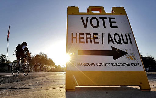 In this Aug. 30, 2016 file photo, a cyclist rides past a sign directing voters to a primary election voting station early, in Phoenix. Early voting kicks off next week in North Carolina, the first in a two-month run of voting through key swing states where non-whites and young adults could give one of the presidential campaigns a decisive advantage before Election Day.