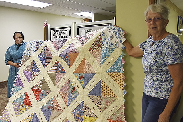 Jo Warnke, right, and Anna Martin hold up a quilt Martin and her daughter put together from found quilt blocks. Warnke is with the Festival of Sharing program and encouraged the women to put the quilt up for auction for the charity.