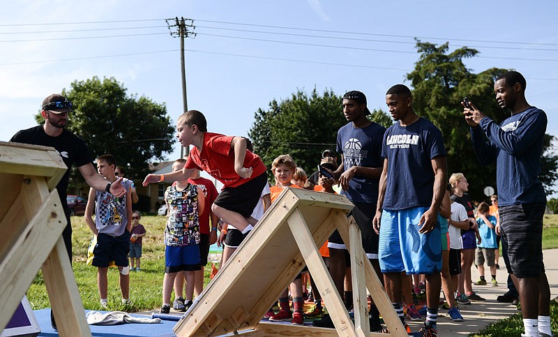 Lincoln University basketball players Victor Alston, right, and Darrius Spencer encourage Blaze Gilzow as he gets in position to jump across platforms through an obstacle course Saturday in the Catch Me if You Can fun run for kids. A
few Lincoln students volunteered their time to help Gilzow, who has a heart condition, finish the race.