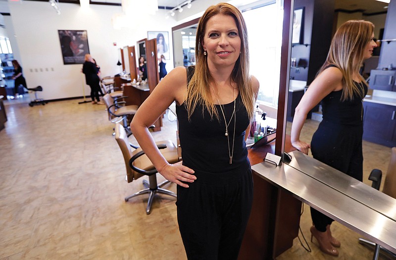 In this Tuesday, Aug. 23, 2016, photo, Christine Perkins, who owns Pyara Spa and Salons at two locations in the Boston area, poses at a stylist station at her salon in Burlington, Mass. Perkins struggles to find candidates to style hair, do manicures and give massages, in part because some beauty schools in the region have closed. 
