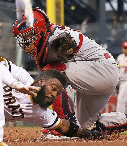 Pittsburgh Pirates' Josh Harrison, bottom, scores around the tag of St. Louis Cardinals catcher Yadier Molina during the first inning of a baseball game in Pittsburgh, Wednesday, Sept. 7, 2016.