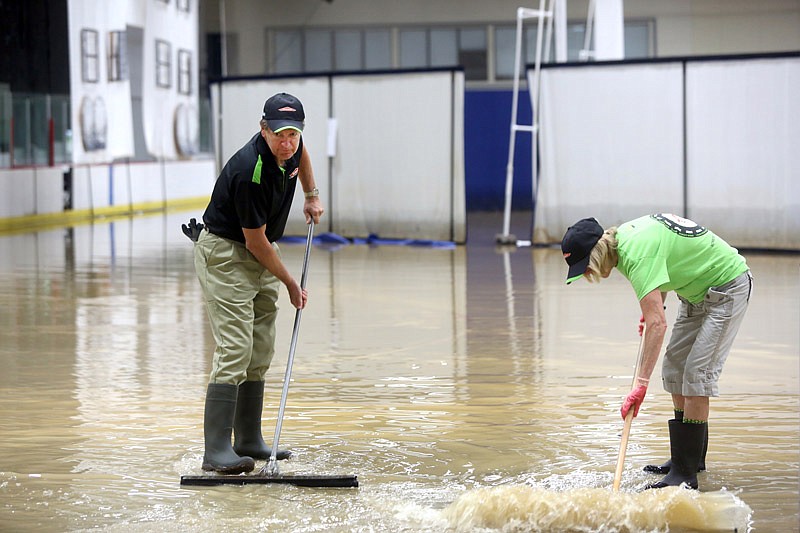 David Kirk, left, and Marlene Kirk, right, sweep floodwater filling the Washington Park Ice Arena in Jefferson City, Missouri on Saturday September 9, 2016. Significant flooding has occurred twice in the past six weeks.