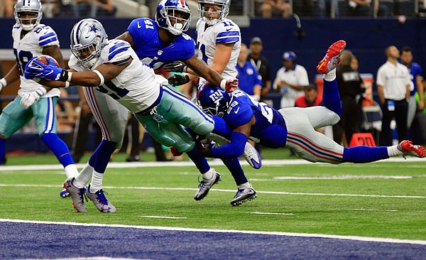Cowboys running back Ezekiel Elliott leaps into the end zone after getting past Giants teammates Dominique Rodgers-Cromartie and Nat Berhe during the second half of Sunday's game in Arlington, Texas.