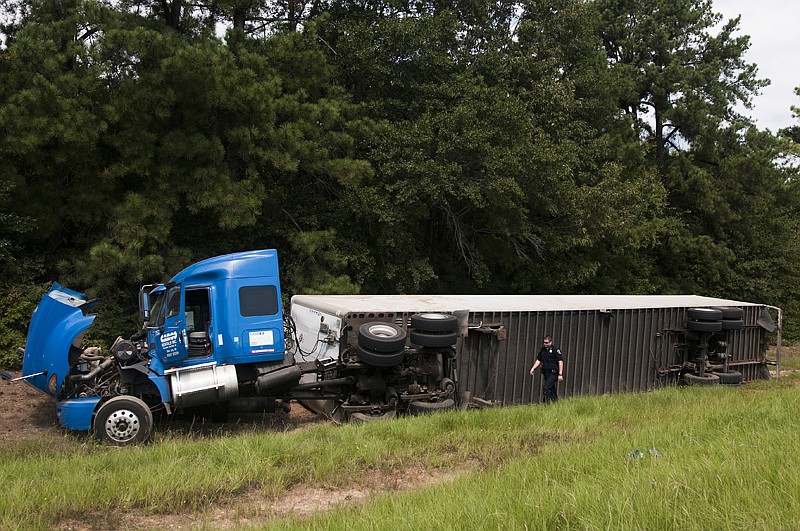 A member of the Texarkana, Ark., Police Department inspects the scene of an 18 wheeler that ran off the road Monday on Interstate 49. The driver was not injured in the accident. 