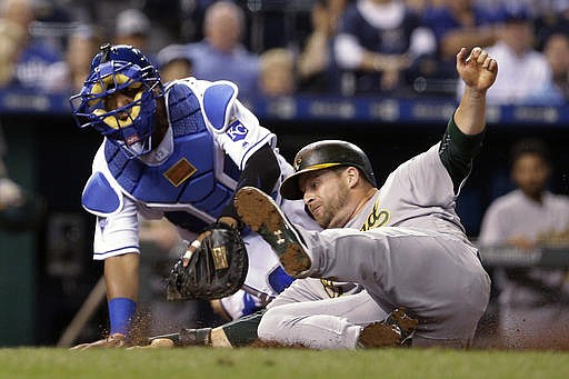 Oakland Athletics' Stephen Vogt beats the tag at home by Kansas City Royals catcher Salvador Perez to score on a two-run single by Khris Davis during the eighth inning of a baseball game against the Kansas City Royals on Wednesday, Sept. 14, 2016, in Kansas City, Mo.