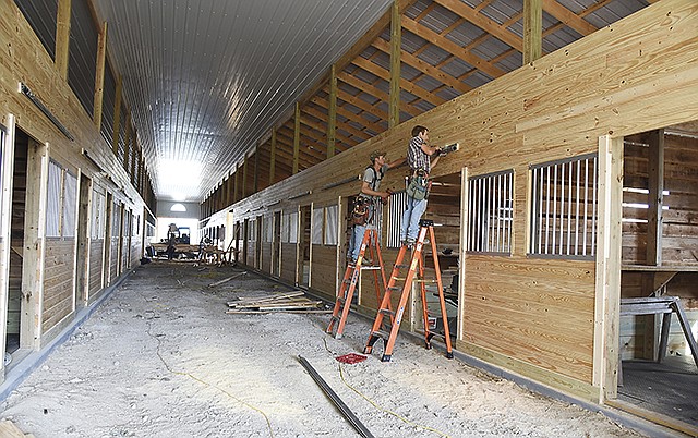 Marlin Kilmer, near, and Jay Rissler attach the door tracks above stalls Wednesday as contruction of the new arena and boarding stables at Fairview Farm in New Bloomfield continues. Both work for Sloan Builders in Fortuna and are rebuilding after a fire destroyed the stables and arena in March. This new facility is 100 feet by 240 feet and will contain a sprinkler system. 