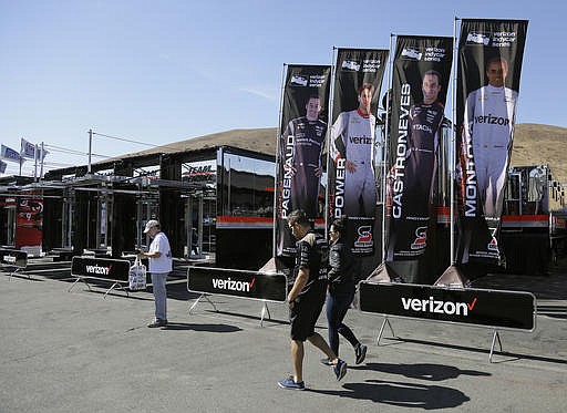 A couple walks past the Team Penske trailers in the garage area during practice for the IndyCar auto race Saturday, Sept. 17, 2016, in Sonoma, Calif. 