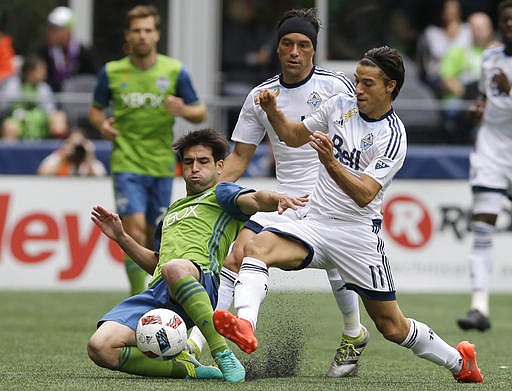 Seattle Sounders midfielder Nicolas Lodeiro, left, is challenged by Vancouver Whitecaps forward Nicolas Mezquida, right, and midfielder Christian Bolanos, center, in the first half of an MLS soccer match, Saturday, Sept. 17, 2016, in Seattle.
