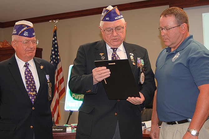From left, Bryce Lockwood and John Dismer, members of the Military Order of the Purple Heart, present a commemorative plaque to Holts Summit Mayor Landon Oxley. 