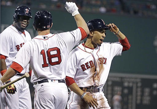 Boston Red Sox's Mookie Betts, right, celebrates with David Ortiz, left, and Aaron Hill (18) after he and Ortiz scored on a single by Hanley Ramirez in the first inning of a baseball game against the Baltimore Orioles at Fenway Park, Monday, Sept. 12, 2016, in Boston.